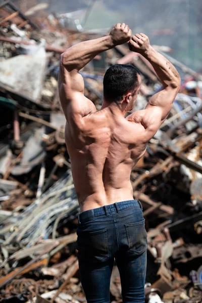 Young Man Standing Strong Old Scrap Metal Garage Flexing Muscles — Stockfoto