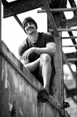 Genç kaslı adam egzersizden sonra depoda dinleniyor - Fiziksel olarak fit bir gencin portresi