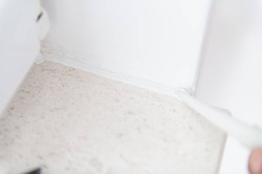 İnşaat işçisi evde pencere onarımı ve montajı için silikon tüp kullanıyor