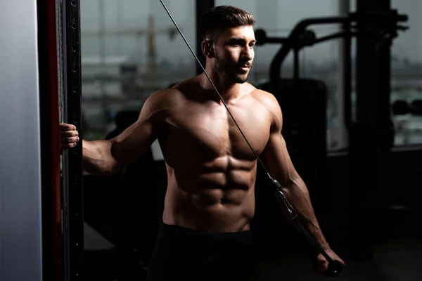健身房里的男人在带缆绳的机器上进行三头肌运动 — 图库照片