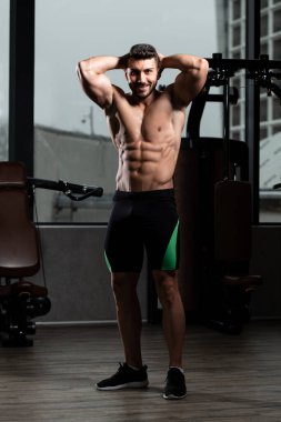 Yakışıklı Genç Adam Spor Salonunda Güçlü Duruyor ve Kaslarını Geriyor - Kas Atletik Vücut Geliştirici Spor Sonrası Spor Pozisyonu