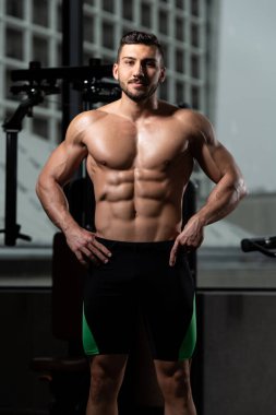 Yakışıklı Genç Adam Spor Salonunda Güçlü Duruyor ve Kaslarını Geriyor - Kas Atletik Vücut Geliştirici Spor Sonrası Spor Pozisyonu