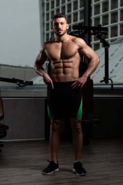 İyi eğitilmiş vücudunu gösteren genç bir adamın portresi - kaslı atletik vücut geliştirici spor sonrası vücut geliştirme modelliği pozu