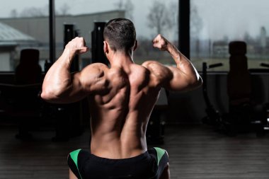 Yakışıklı Genç Adam Spor Salonunda Güçlü Duruyor ve Kaslarını Geriyor - Kas Atletik Vücut Geliştirici Spor Sonrası Spor Pozisyonu