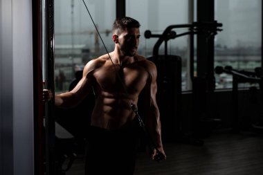 Spor salonundaki adam spor salonunda kablolu TV ile trisepslerini çalıştırıyor.