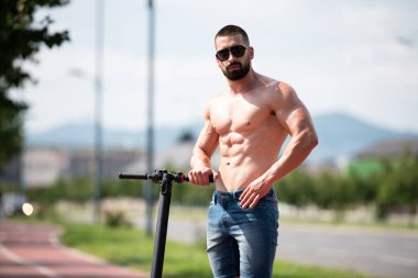 Genç Çekici Sporcu Parlak Güneş Günü 'nde Scooter' ını sokakta kullandıktan sonra dinleniyor.