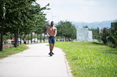 Yazın sokakta elektrikli scooter süren genç adam.