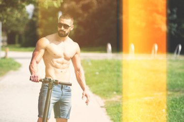 Genç adam yazın sokakta elektrikli scooter sürdükten sonra dinleniyor.