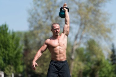 Kettle Bell 'le antrenman yapan adam vücut geliştirici. Kettle Bell' le ağırlık egzersizi yapıyor.