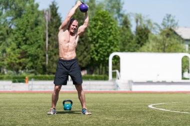 Kettle Bell 'le antrenman yapan adam vücut geliştirici. Kettle Bell' le ağırlık egzersizi yapıyor.