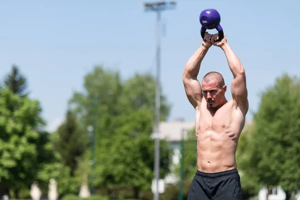 Mann Trainiert Mit Wasserkocher Freien Und Beugt Muskeln Vor Muskulös — Stockfoto