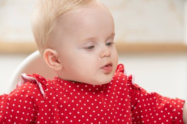 Anne, bebeğini evde yiyecekle besledikten sonra bebeğin ağzını peçeteyle siliyor.