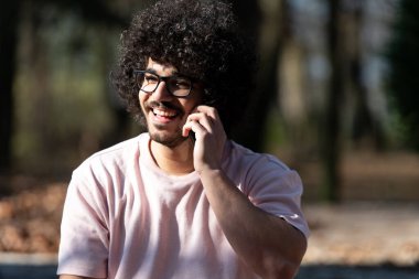 Güz boyunca cep telefonuyla konuşan ve dışarıda oturan yakışıklı afro adamın portresi.