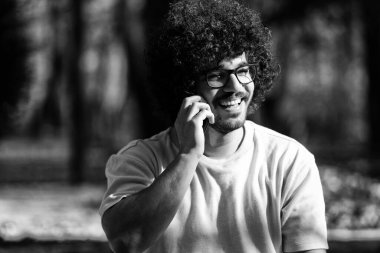 Güz boyunca cep telefonuyla konuşan ve dışarıda oturan yakışıklı afro adamın portresi.