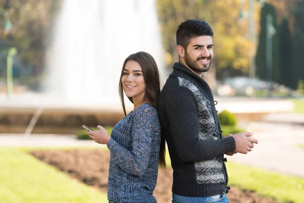 Young Couple Standing Beautiful Autumn Day Typing Phone Park — Stock Photo, Image