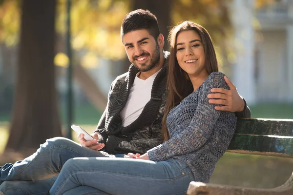 Young Couple Sitting Bench Beautiful Autumn Day Typing Phone Park — 스톡 사진