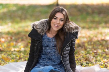 Güzel bir sonbahar gününde battaniyede oturan genç çift