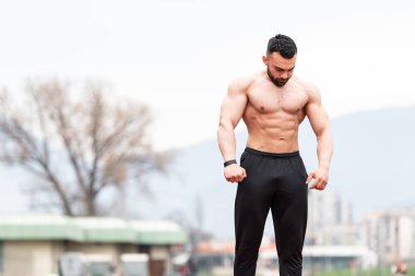 Yakışıklı Sakallı Adam güçlü duruyor ve açık havada poz veriyor.