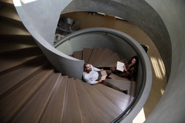 İki Kolej Öğrencisi Spiral Merdivenler Mimarisi hakkında kitap okuyor Okul için Sanat Öğrenme Dersleri