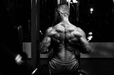 Yakışıklı Vücut Geliştirici Makineye Geri Dönmek İçin Ağır Ağırlık Egzersizi Yapıyor