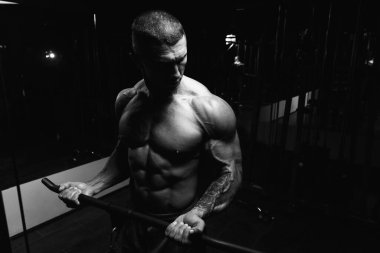 Spor salonundaki adam, spor salonundaki kablolu televizyonuyla bisiklete biniyor.