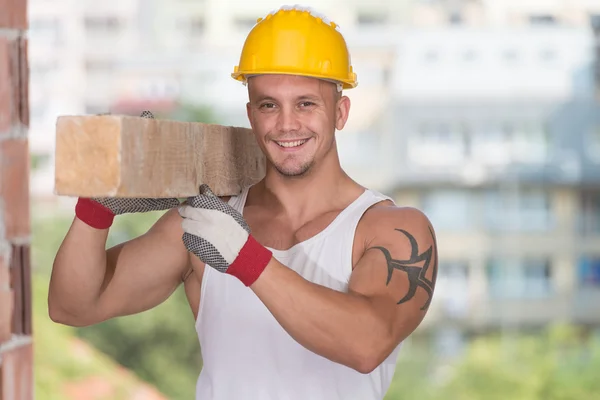 Jonge knappe bouwer met houten planken — Stockfoto