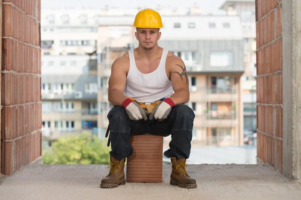 Constructor cansada descansando sobre ladrillo — Stock fotografie