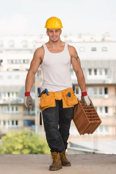 Junger gutaussehender Bauunternehmer mit Backstein — Stockfoto