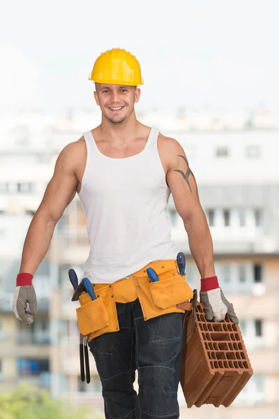 Joven constructor guapo con ladrillo —  Fotos de Stock