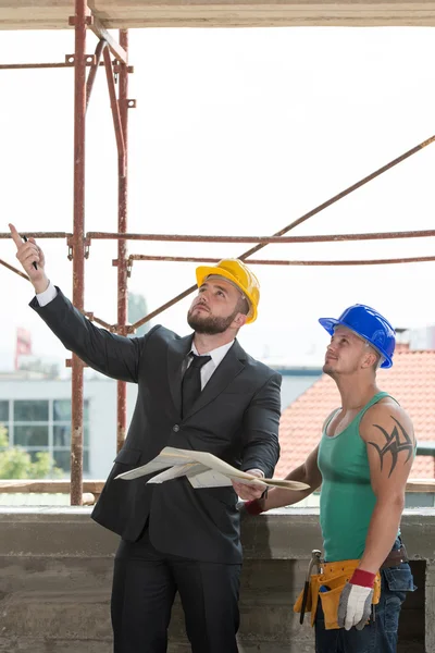 Engenheiro e trabalhador de construção discutindo um projeto — Fotografia de Stock