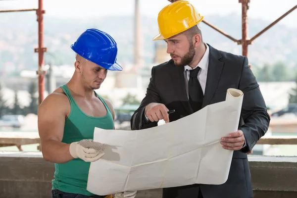 Engenheiro e trabalhador de construção discutindo um projeto — Fotografia de Stock