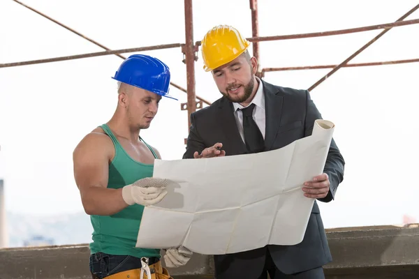 Engenheiro e trabalhador de construção discutindo um projeto — Fotografia de Stock