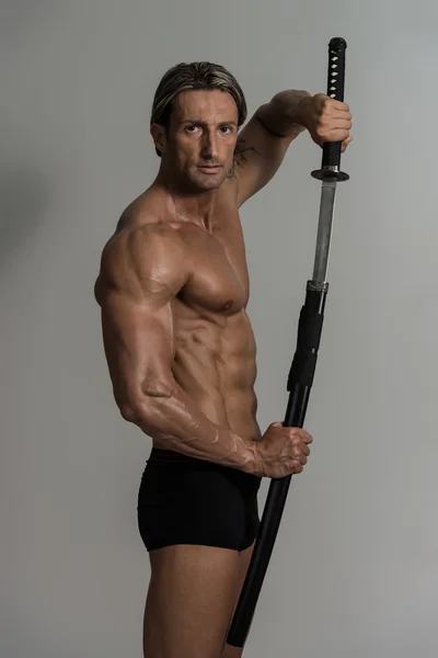 Musculado modelo masculino no estúdio com uma espada — Fotografia de Stock