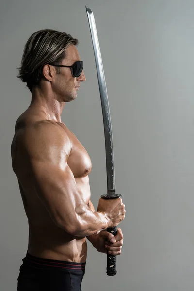Musculado modelo masculino no estúdio com uma espada — Fotografia de Stock