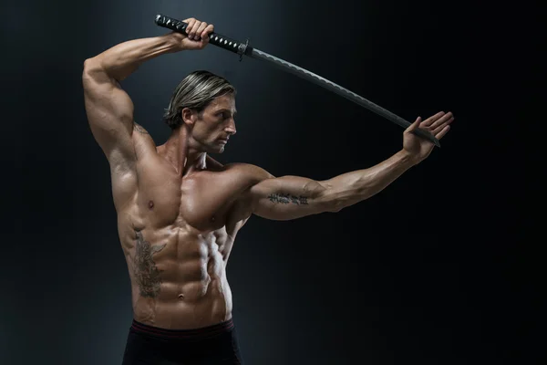 Мускулистый мужчина-модель в студии с мечом — стоковое фото