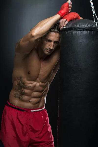 Мускулистый боксер без рубашки с боксерской грушей в спортзале — стоковое фото