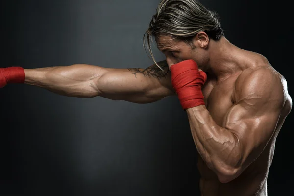 Boxeador muscular sin camisa con saco de boxeo en el gimnasio — Foto de Stock