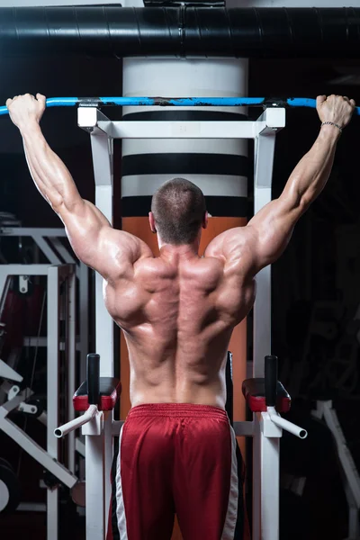 Jovem masculino fazendo exercícios nas costas no ginásio — Fotografia de Stock