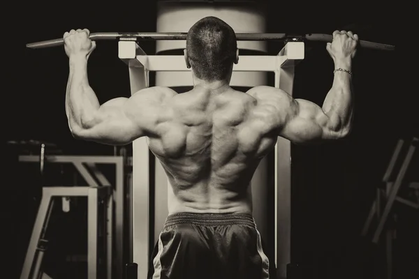 Joven macho haciendo ejercicios de espalda en el gimnasio — Foto de Stock