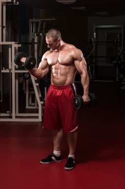 Kaslı adam pazılar için ağır ağırlık egzersizi yapıyor.