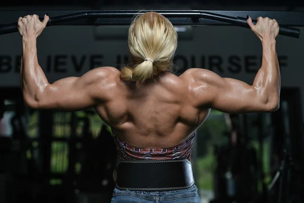 Ung kvinna gör ryggen övningar i gymmet — Stockfoto