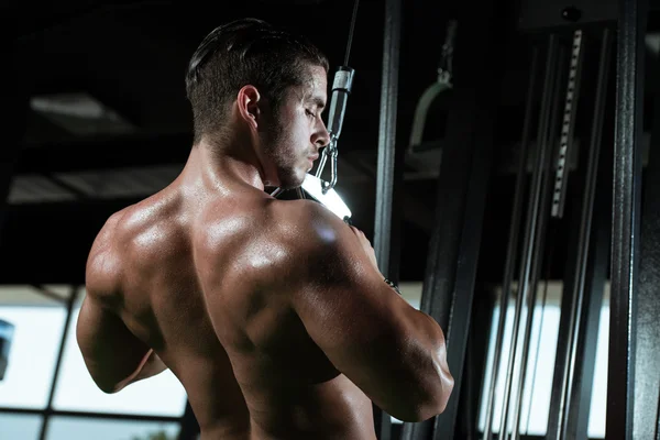 Joven macho haciendo ejercicios de espalda en el gimnasio — Foto de Stock