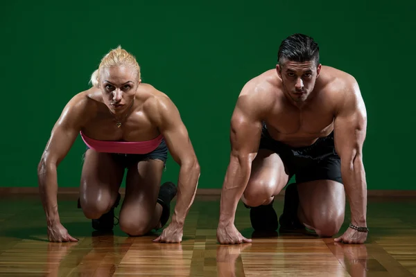 Strong Muscular Couple Kneeling On The Floor Stock Picture