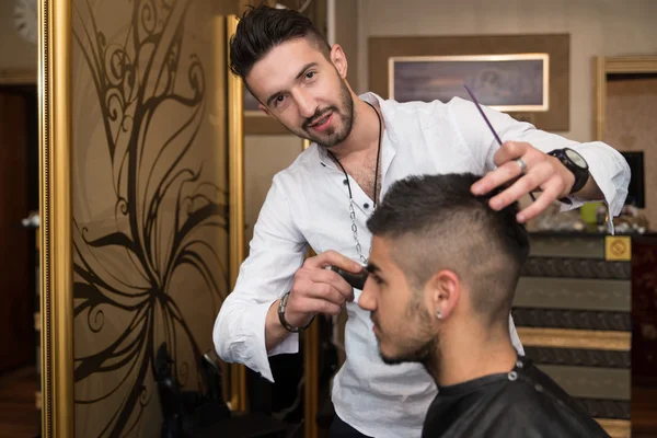 Cabeleireiro limpeza jovem após corte de cabelo — Fotografia de Stock