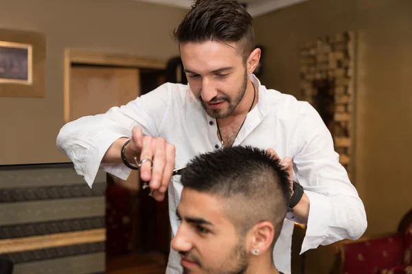 Peluquero haciendo corte de pelo a hombre joven —  Fotos de Stock