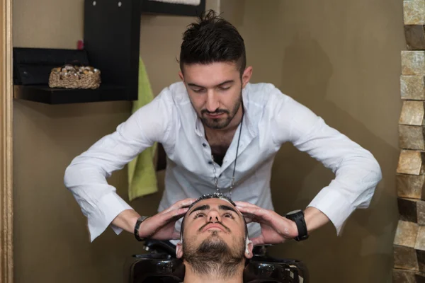 Lächelnder Mann lässt sich beim Friseur die Haare waschen — Stockfoto