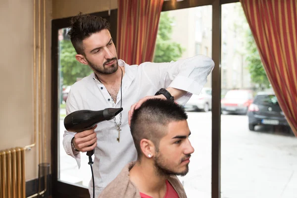 Styliste séchant les cheveux d'un client masculin — Photo