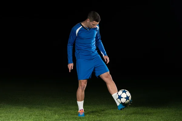 Jugador de fútbol profesional pateando pelota aislado en negro — Foto de Stock