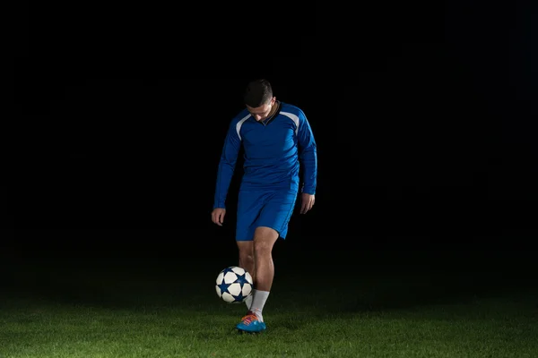 Fotbollspelare med en boll på svart bakgrund — Stockfoto