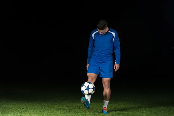 Fotbollspelare med en boll på svart bakgrund — Stockfoto